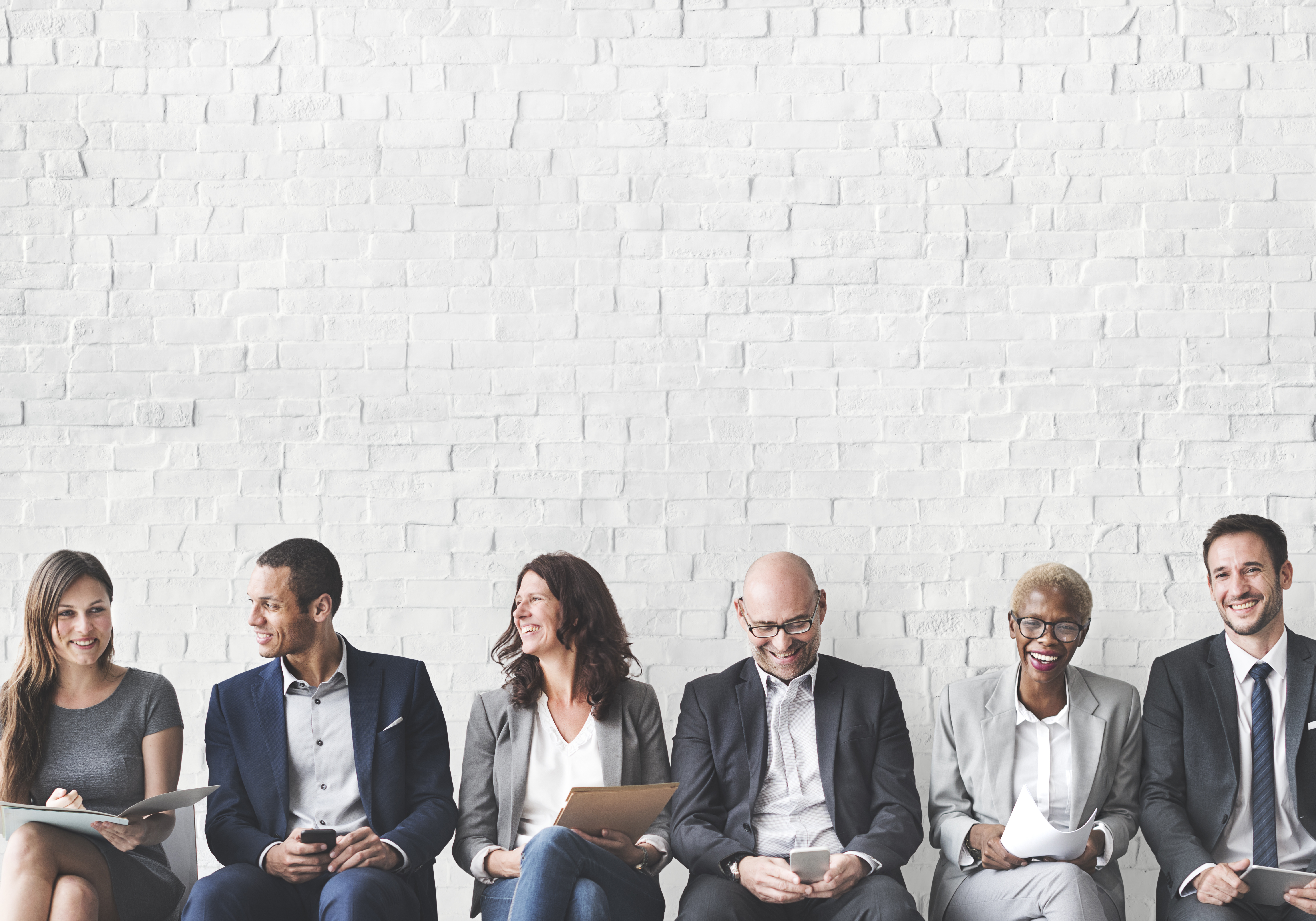 Business people sitting down against a brick wall backdrop